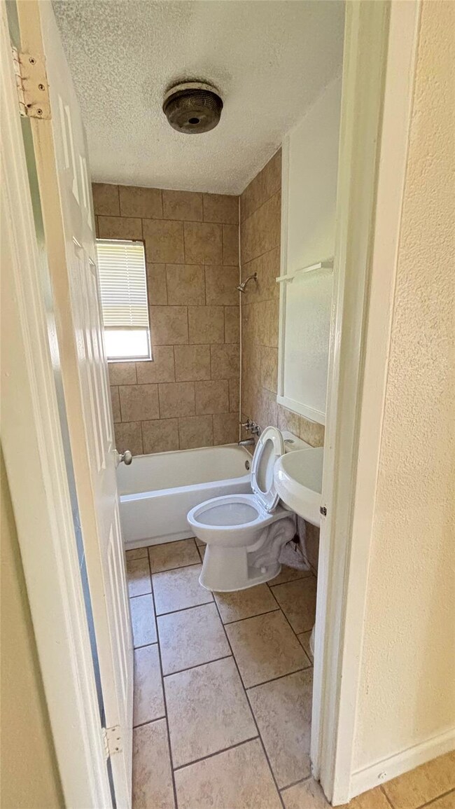Full bathroom with a textured ceiling, a sink, sh