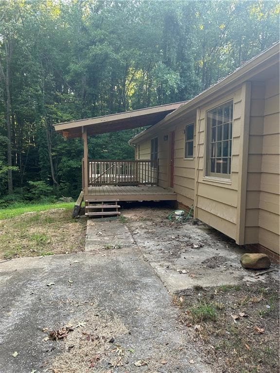 View of side of property with a deck and a wooded 