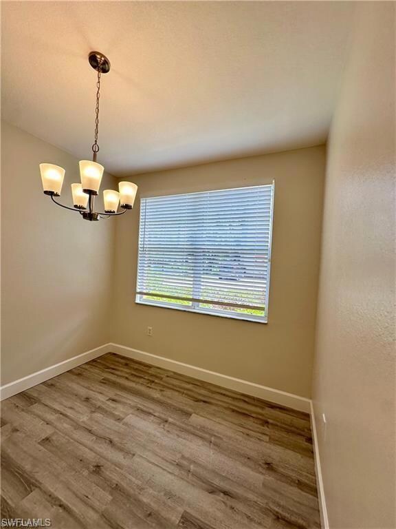 Empty room featuring baseboards, a chandelier, and