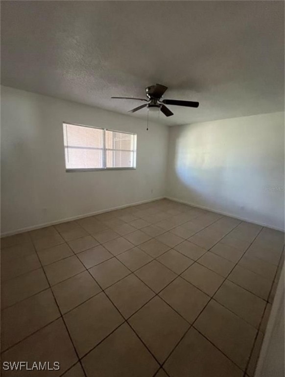 Empty room with a ceiling fan and light tile patte