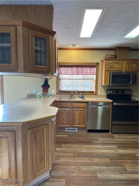 Kitchen featuring brown cabinets, light countertops, stove, dishwashing machine, and a textured ceiling