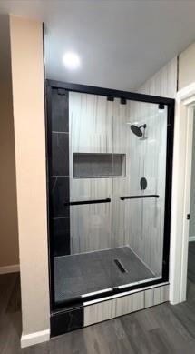 Full bath with wood finished floors and a shower stall