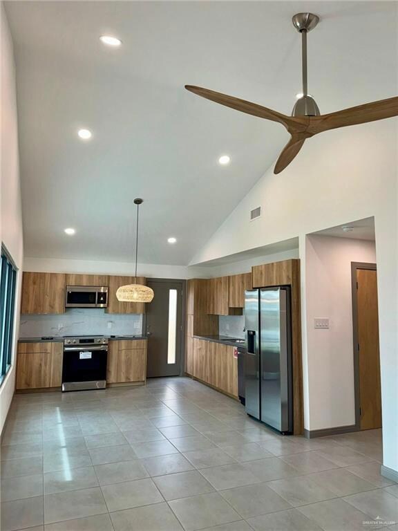 Kitchen featuring stainless steel appliances, pendant lighting, high vaulted ceiling, light tile flooring, and ceiling fan