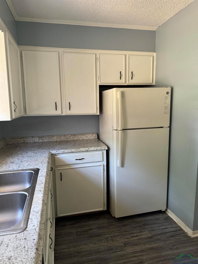 Kitchen featuring white refrigerator, dark hardwoo