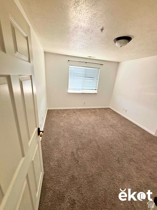 Unfurnished room with dark colored carpet and a textured ceiling