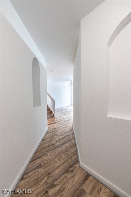 Corridor featuring wood finished floors and arched