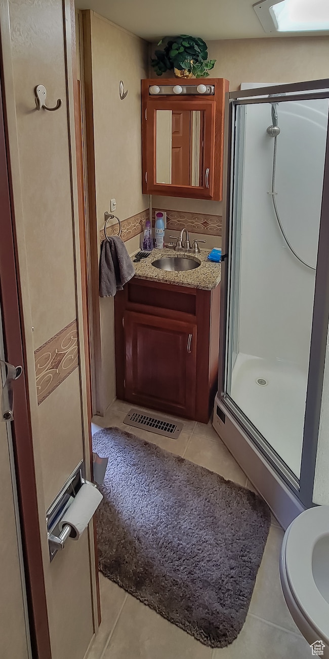 Full bath with tile patterned floors, a stall shower, vanity, and a skylight
