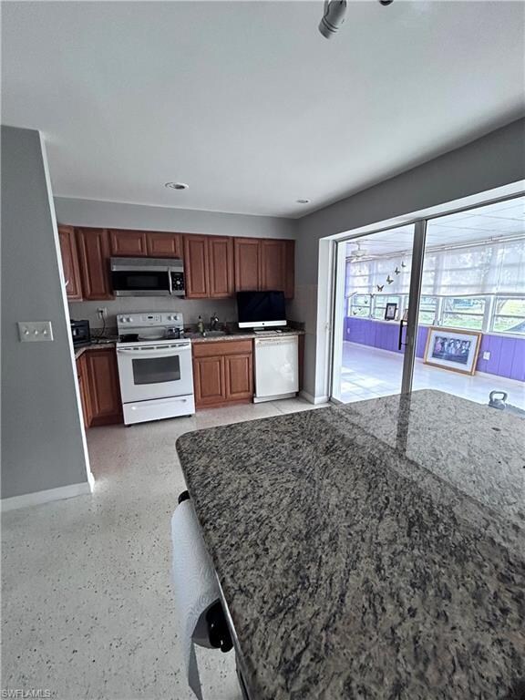 Kitchen featuring white appliances, dark stone cou