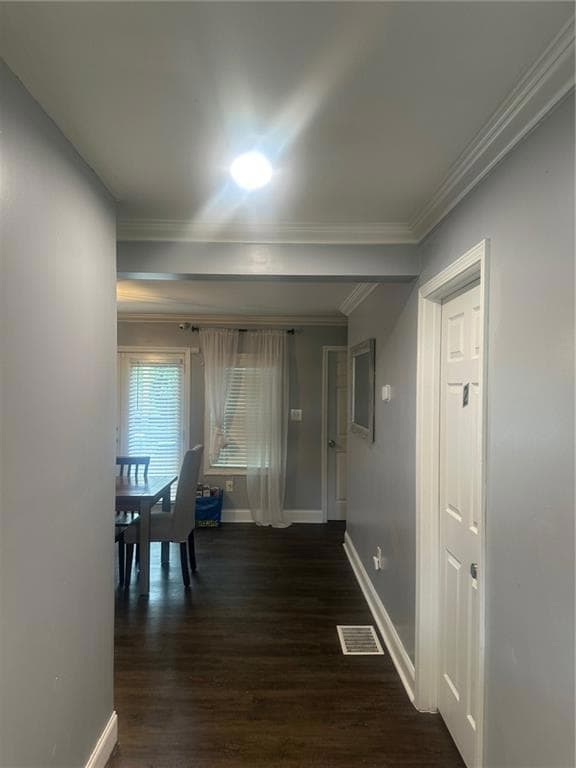 Corridor featuring dark wood finished floors, crown molding, and baseboards