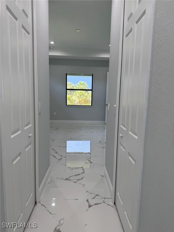 Hall featuring baseboards, marble tiled flooring,