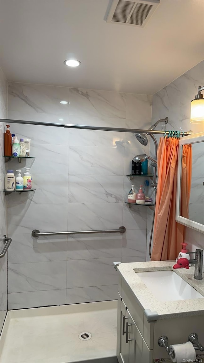 Bathroom with a shower stall, vanity, and recessed lighting