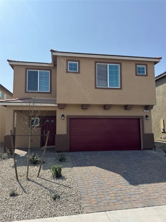View of front facade featuring stucco siding, a ga