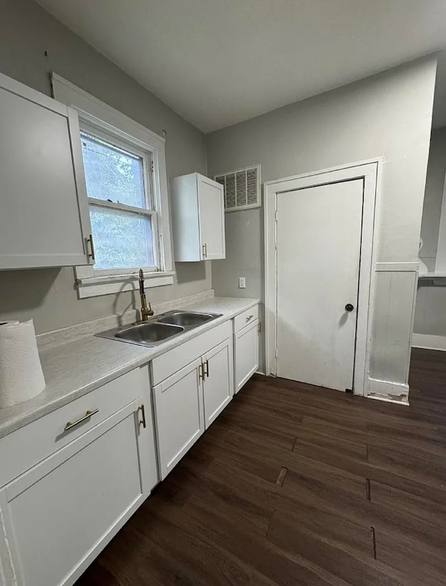 Kitchen with white cabinetry, light countertops, and dark wood-style floors