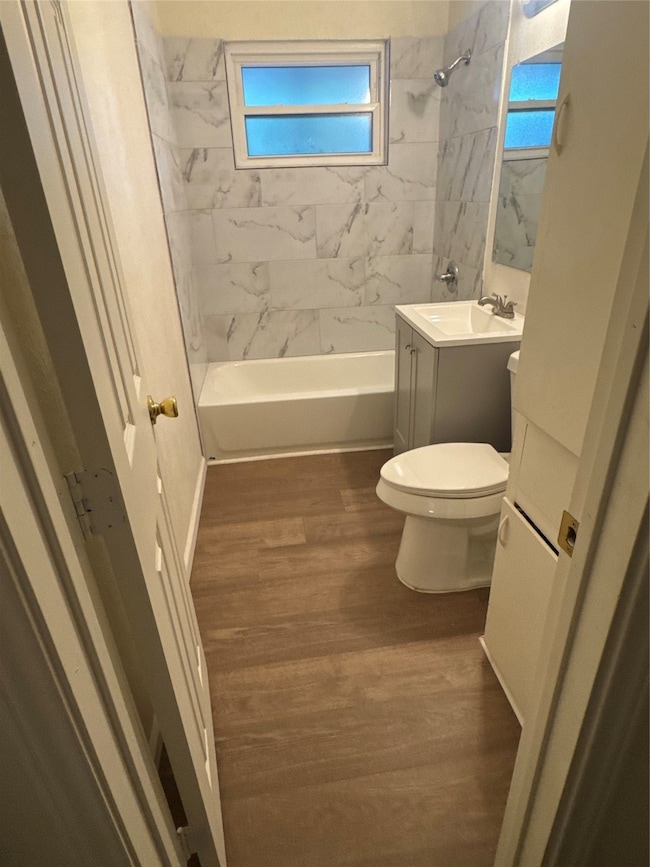 Bathroom featuring vanity, washtub / shower combination, and dark wood-type flooring