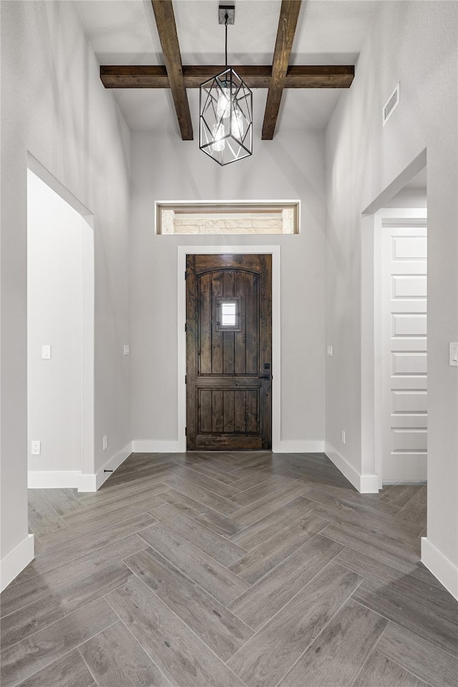 Foyer entrance featuring beam ceiling, baseboards