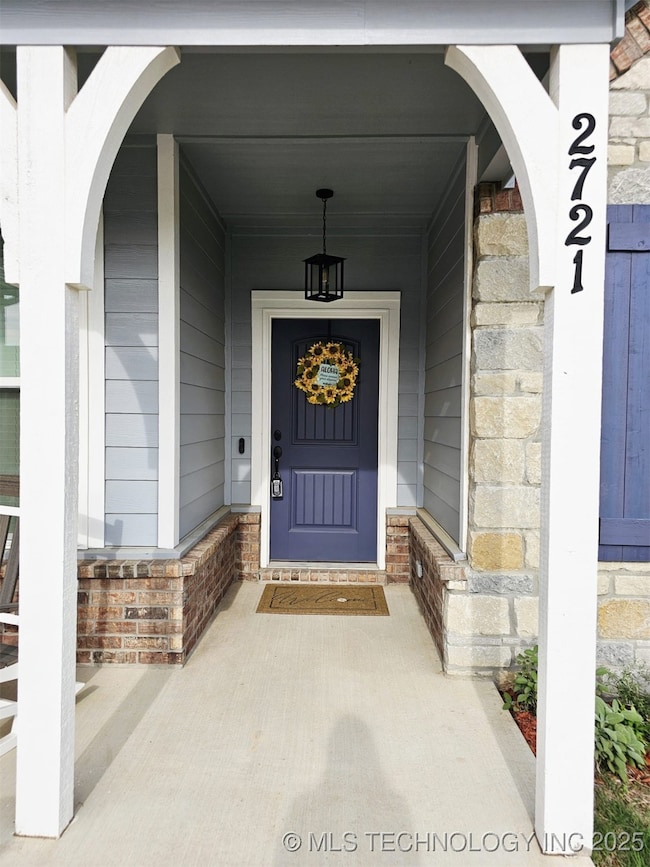 Property entrance featuring covered porch and stone siding