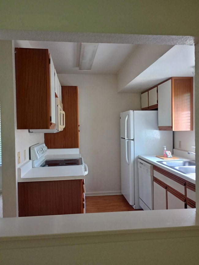 Kitchen featuring white appliances, a sink, light