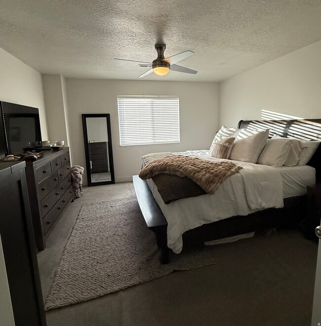 Carpeted bedroom featuring a textured ceiling and ceiling fan