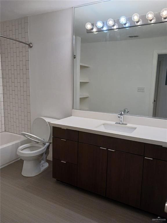 Bathroom featuring visible vents, toilet, wood finished floors, vanity, and shower / bathtub combination