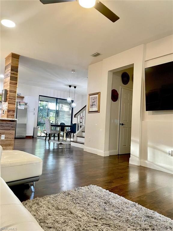 Living room with baseboards, a ceiling fan, wood f