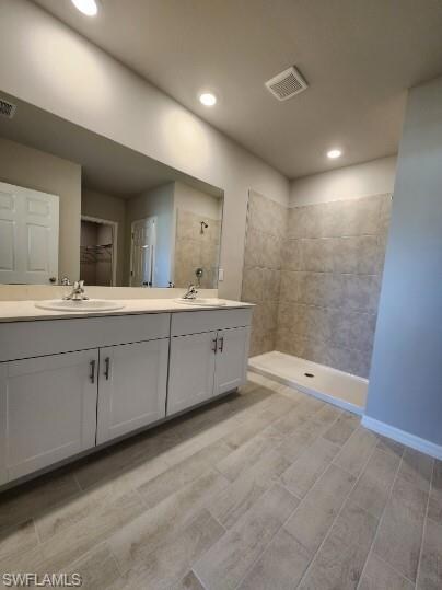 Full bathroom featuring a tile shower, a sink, dou