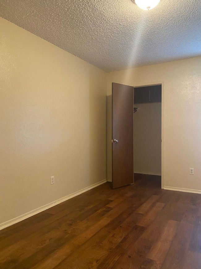 Unfurnished bedroom featuring dark wood-style flo
