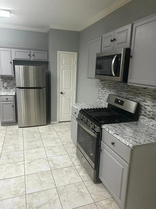 Kitchen with gray cabinetry, appliances with stain