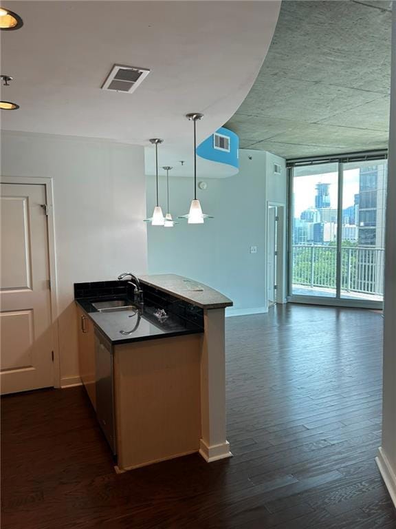 Kitchen featuring a sink, a peninsula, baseboards, dark wood finished floors, and open floor plan