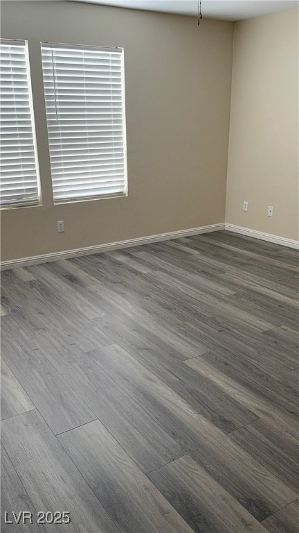 Spare room with dark wood-style flooring and baseb