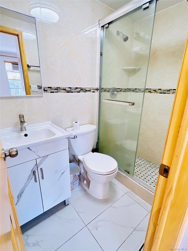 Bathroom with tile walls, vanity, and a shower stall