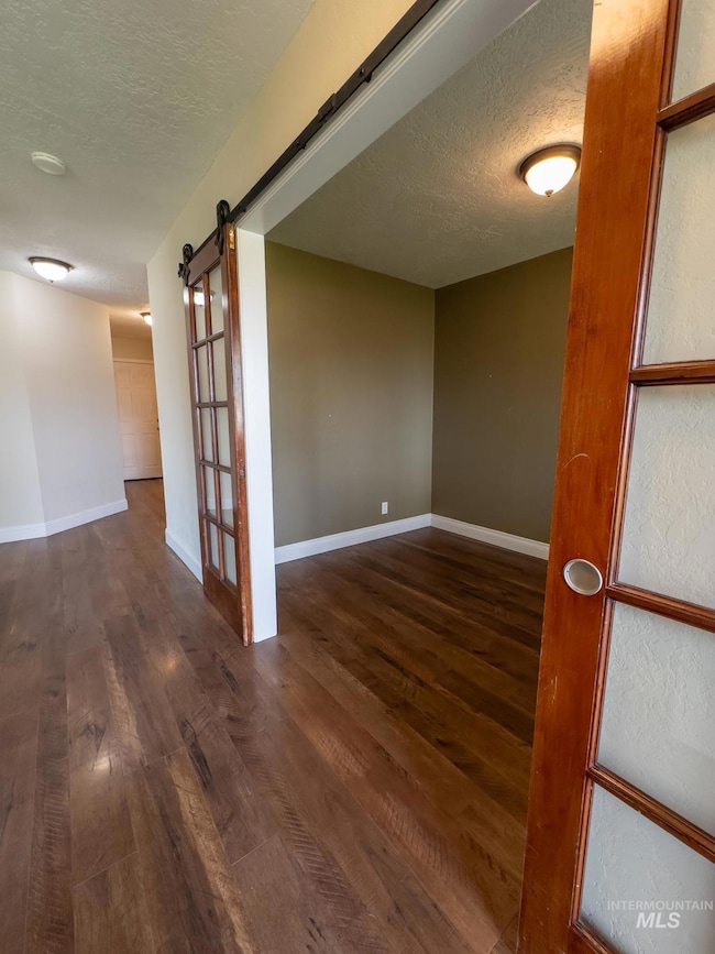 Spare room with a textured ceiling, a barn door, and dark wood-style flooring