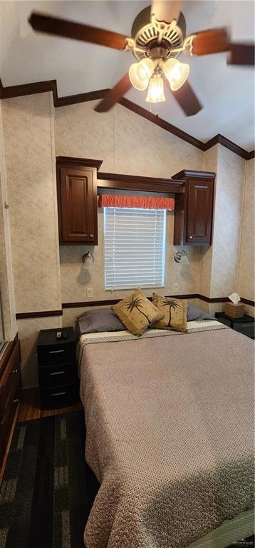 Bedroom with vaulted ceiling, ornamental molding, dark wood-style floors, and a ceiling fan