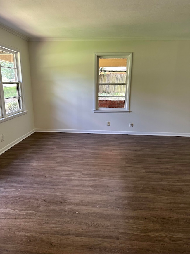 Unfurnished room featuring crown molding and dark wood-type flooring