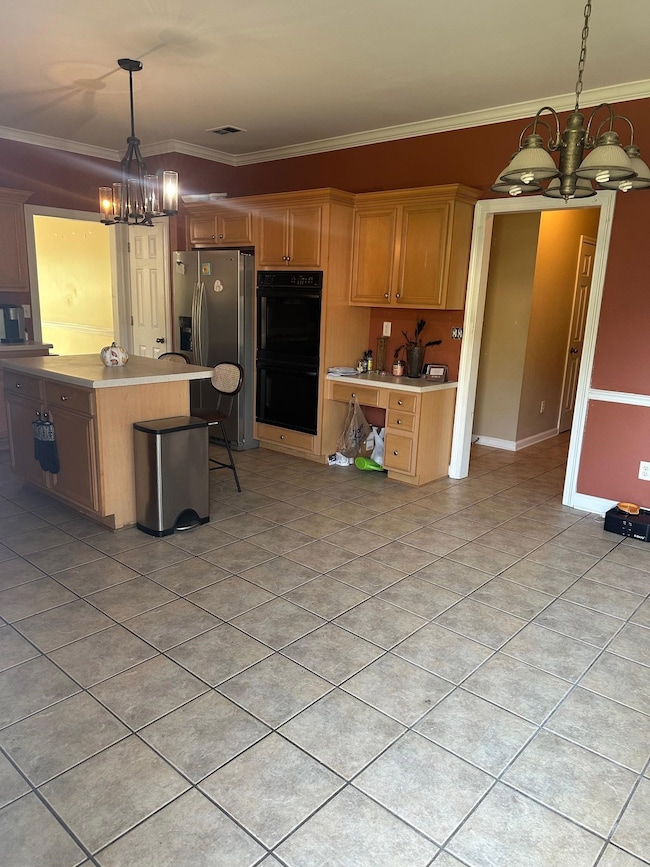 Kitchen with a chandelier, decorative light fixtures, ornamental molding, and light countertops