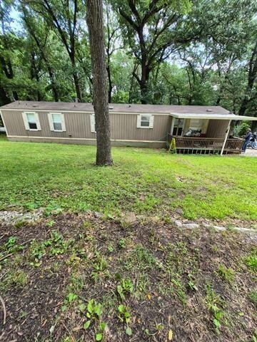 View of front of house featuring a front lawn and view of wooded area