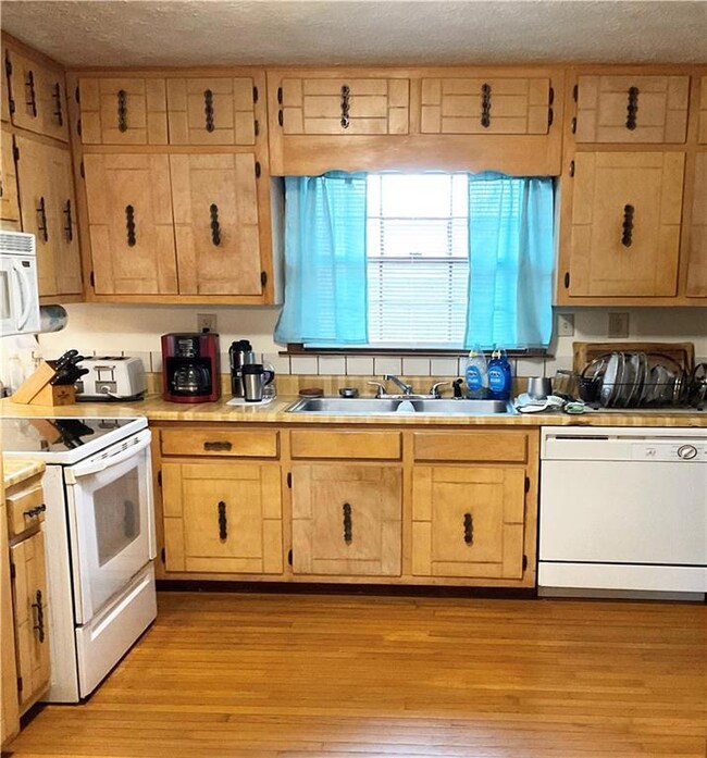 Kitchen featuring sink, white appliances, light ha