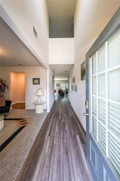 Foyer entrance featuring baseboards, visible vents, a towering ceiling, and dark wood-type flooring