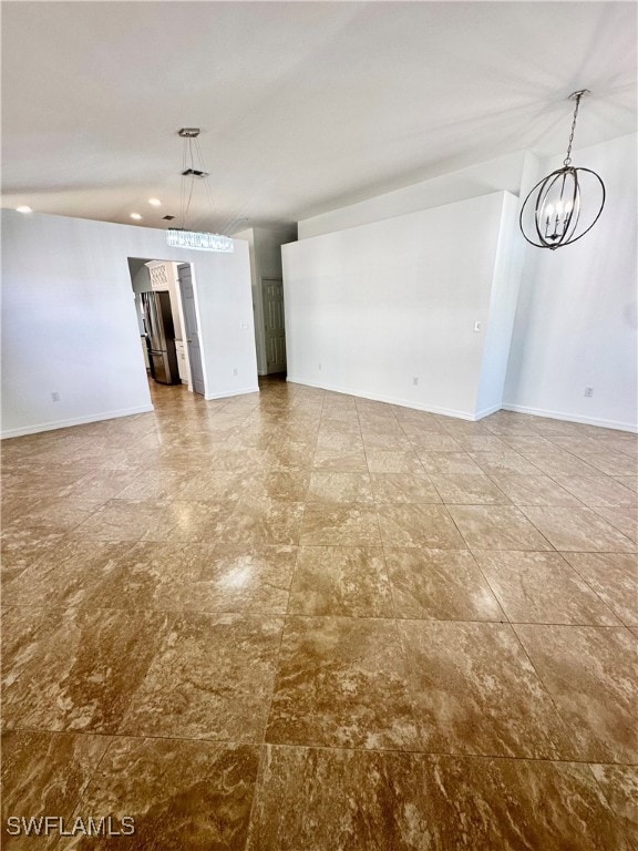 Empty room featuring a chandelier and baseboards