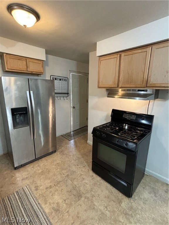 Kitchen featuring refrigerator, light tile flooring, stove, and fume extractor