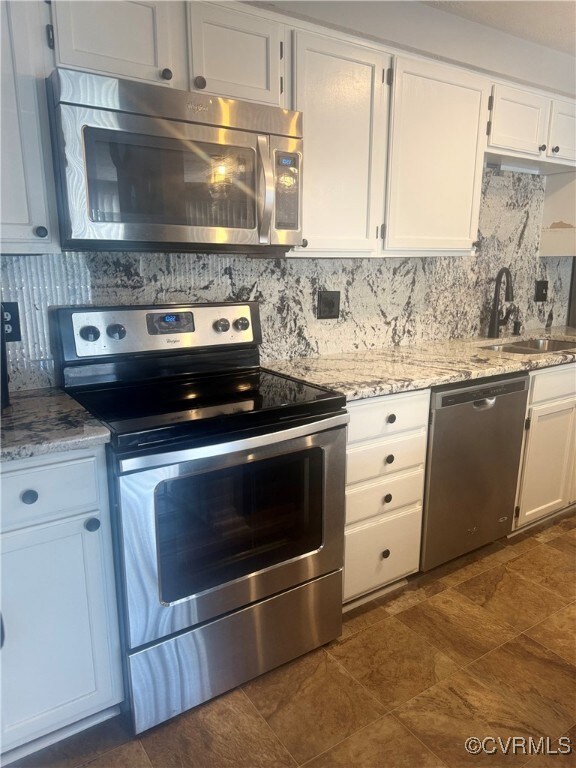Kitchen featuring white cabinets, tasteful backspl