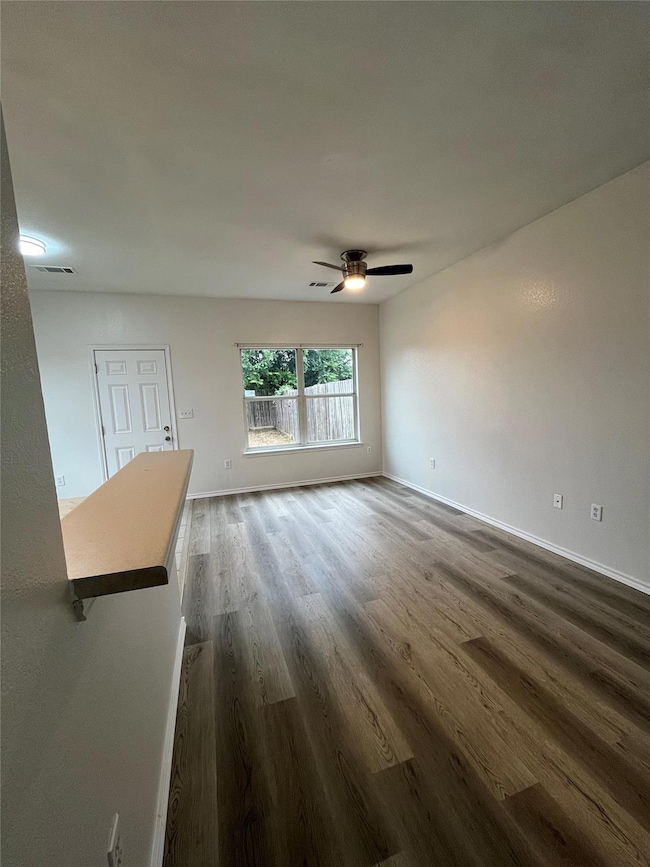 Empty room with dark wood-style floors, a ceiling