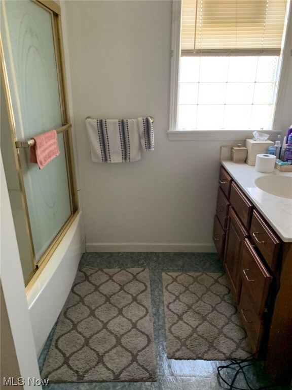 Bathroom featuring enclosed tub / shower combo, a healthy amount of sunlight, tile floors, and vanity