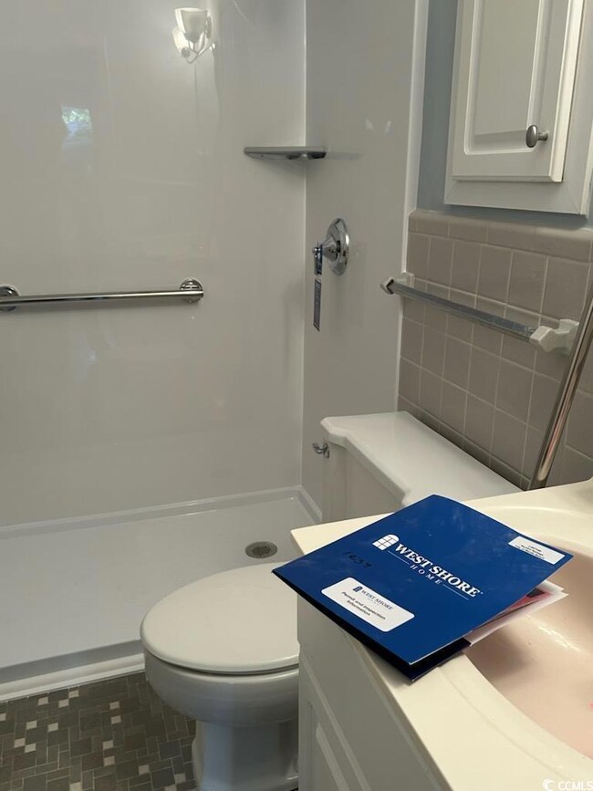 Bathroom featuring vanity, toilet, and a shower