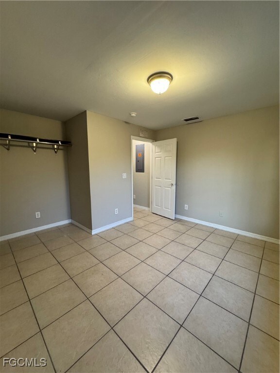 Unfurnished bedroom with light tile patterned floors and electric panel