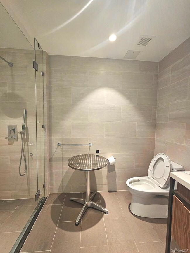 Bathroom with tile walls, a stall shower, vanity, recessed lighting, and tile patterned flooring