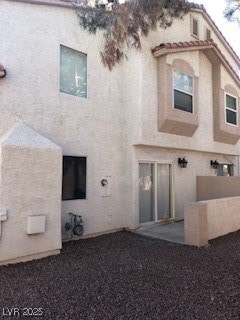 Back of property with a tile roof and stucco sidin
