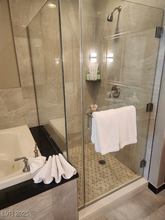Full bathroom featuring a shower stall and a tub w
