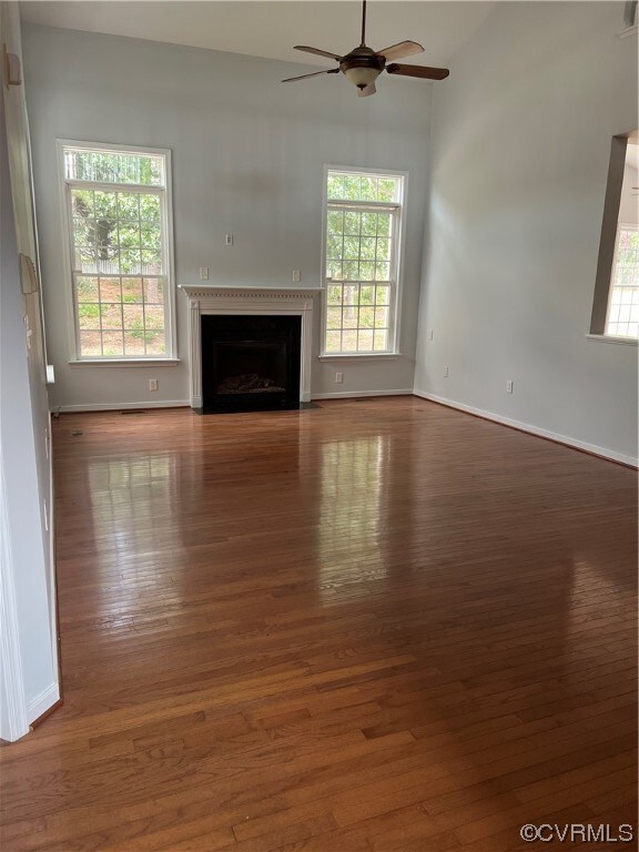 Living room featuring a fireplace, light hardwood floors, and ceiling fan