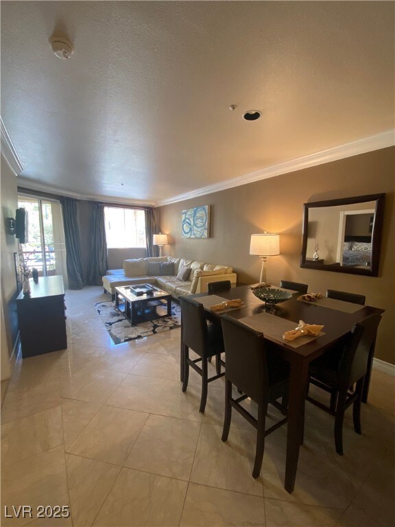 Dining space with a textured ceiling and crown mol