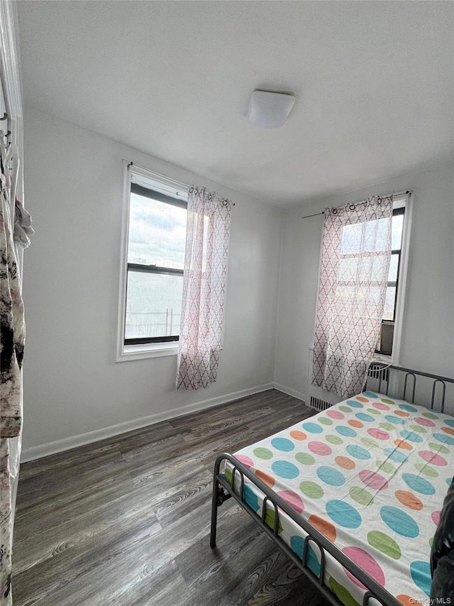 Bedroom with dark wood-style flooring and baseboards
